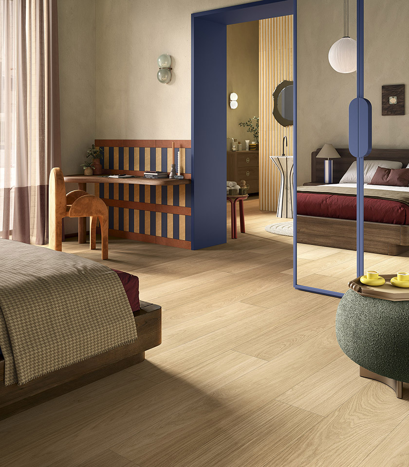 Bio Charme Golden interpretiert die Wärme von Eichenholz in einer hellen, natürlich wirkenden Keramikoberfläche, ideal für einladende Schlafzimmer mit modernem Design.