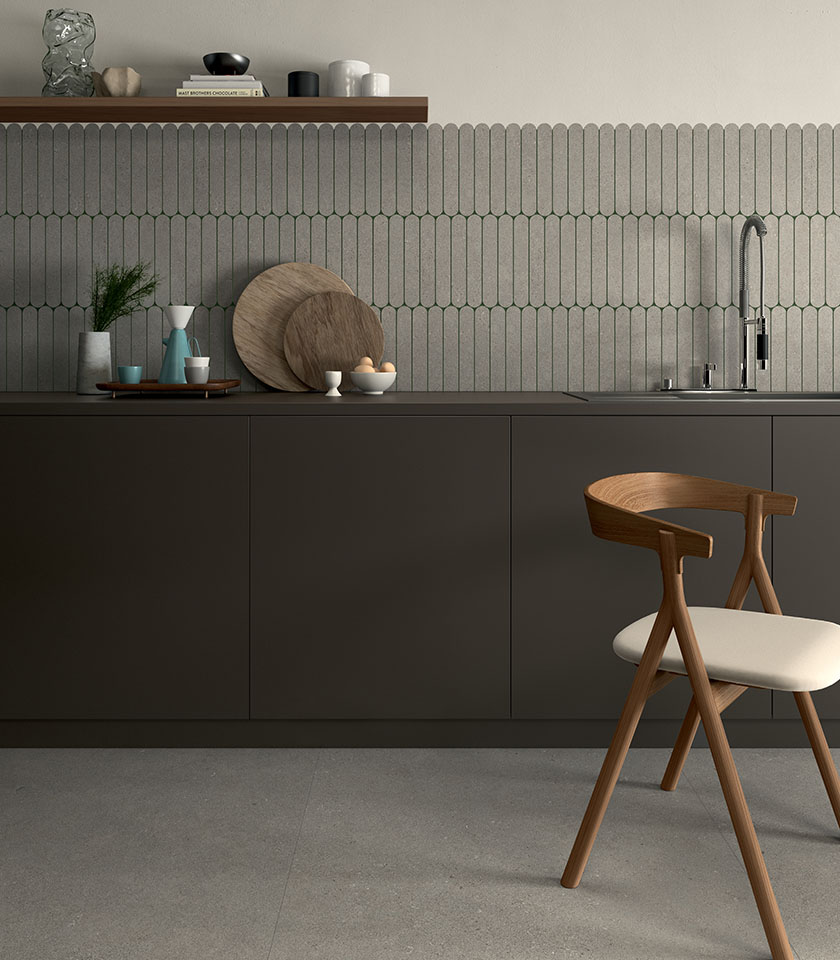 Minimal-Chic-Küche mit Boden in Betonoptik, geometrischer Wandverkleidung Ton in Ton, dunklen Möbeln und reduzierten Designdetails aus Holz.