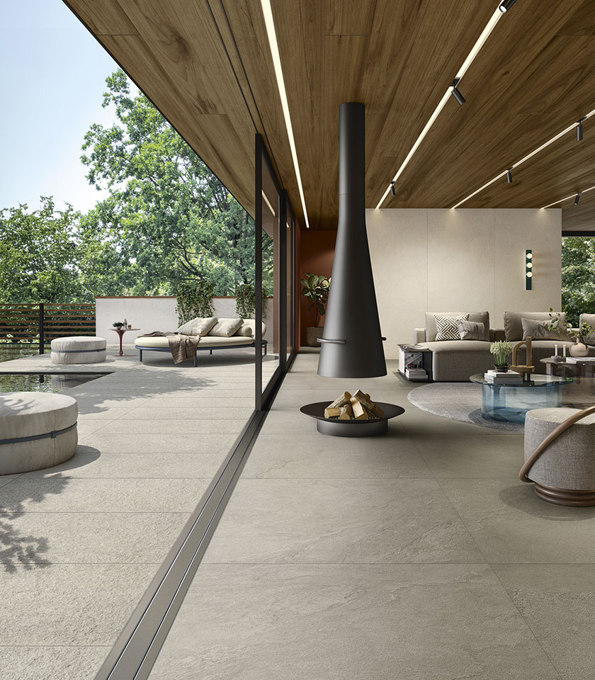 Moderner Indoor-Outdoor-Wohnbereich mit Boden aus der Kollektion Pulse in Steinoptik im Farbton Clay, Clay Rough Oberfläche für den Außenbereich und Wandverkleidungen im Farbton Shell.