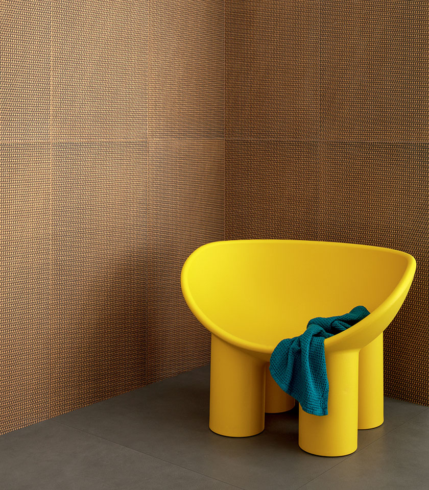 Zeitgemäßes Badezimmer mit dekorativer Wandverkleidung in Orange- und Schwarztönen, gelbem Sessel und blauen Textildetails.