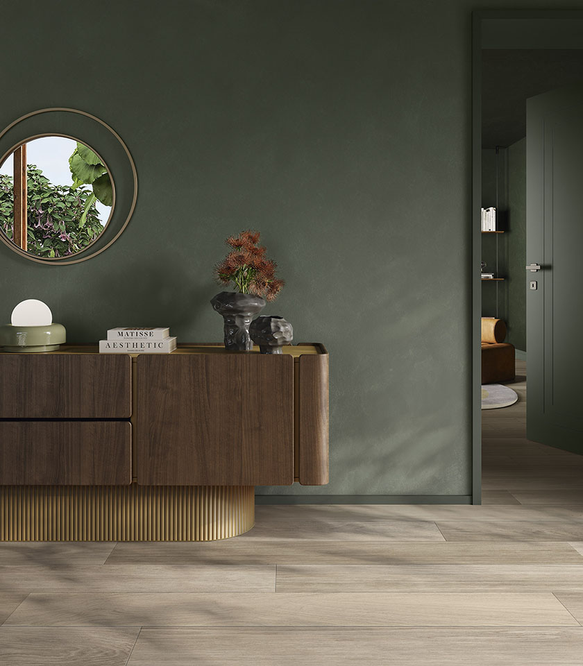 Zeitgemäßer Innenraum mit Biocharme Havana Boden in Holzoptik, salbeigrünen Wänden und eleganten Holzmöbeln.