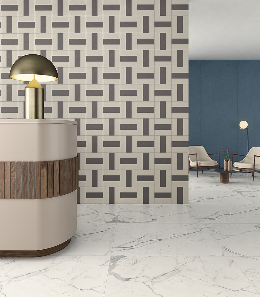 Moderner Empfangsbereich mit Feinsteinzeugboden in Marmoroptik, geometrischer Dekorwand und blauer Wandverkleidung.