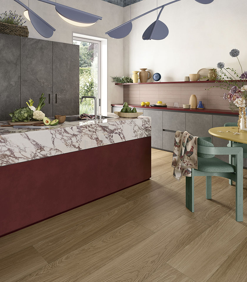 Moderne Küche mit Boden aus der Kollektion Biocharme in Holzoptik im Farbton Bark, Kücheninsel mit Oberfläche aus der Kollektion Noblesse in Marmoroptik Arabesque, Elementen aus der Kollektion Pulse im Farbton Shadow und Wandverkleidung Pigmenti Mauve.
