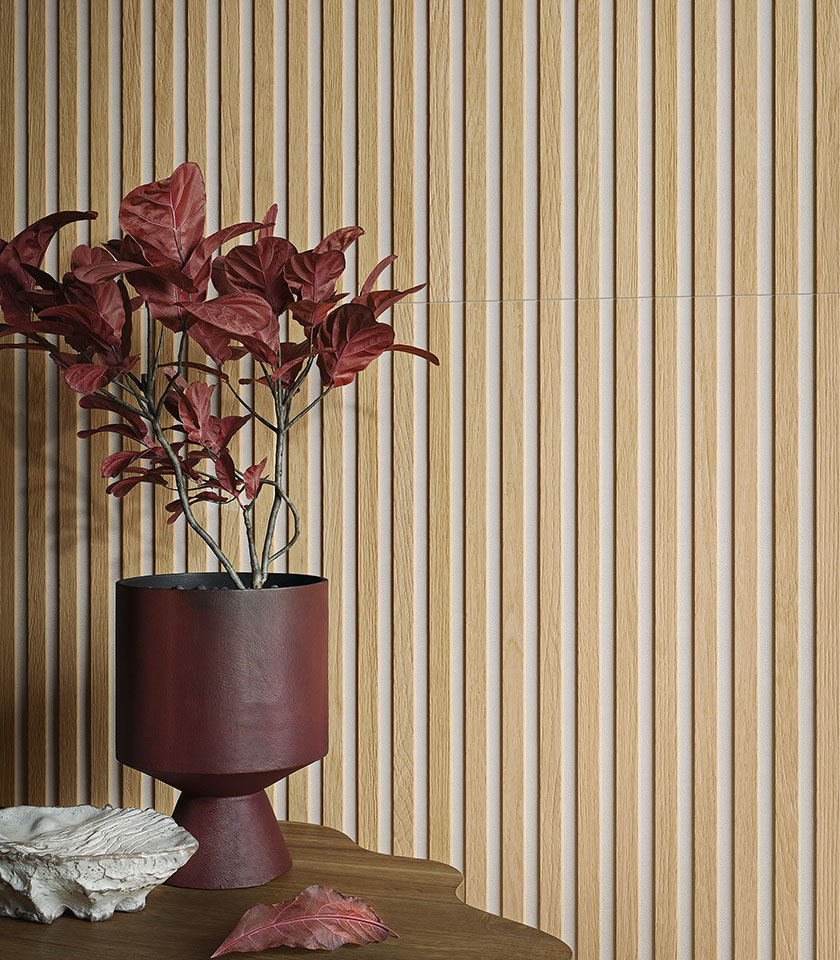 Detail einer dreidimensionalen Wandverkleidung in heller Holzoptik mit bordeauxfarbener Vase und dekorativem Pflanzenarrangement.
