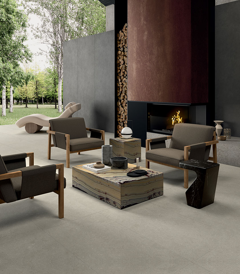 Moderner Außenbereich mit hellem Feinsteinzeugboden, Lounge-Bereich mit Kamin, Designmöbeln und Blick ins Grüne.