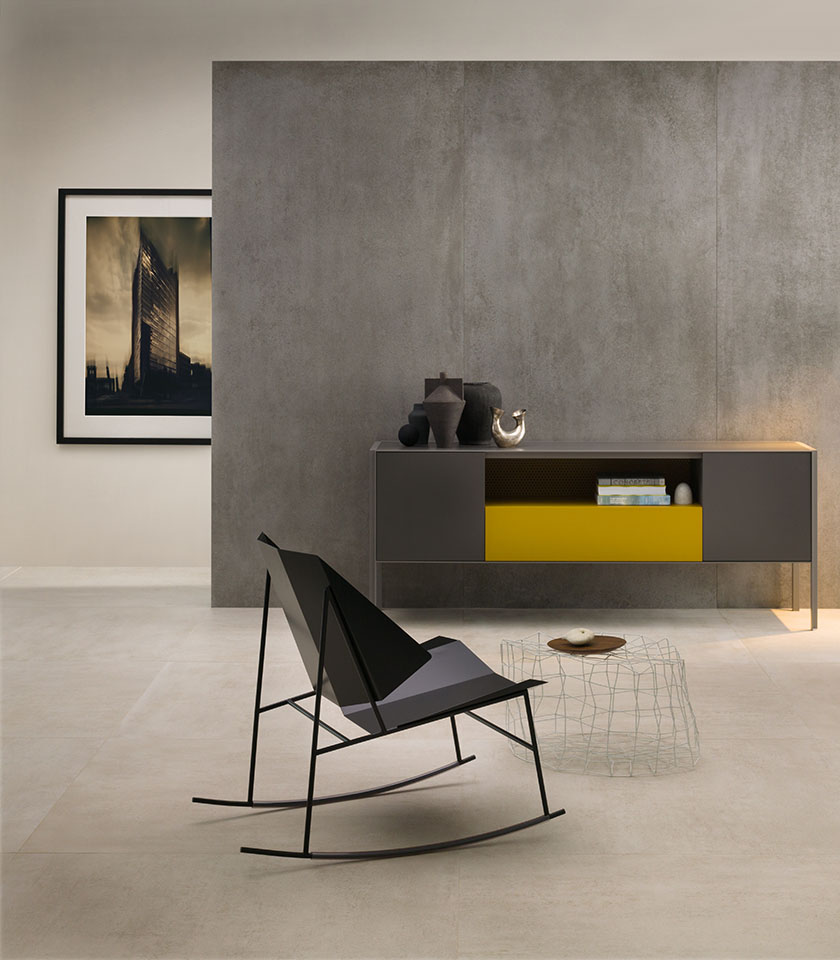 Minimal-Chic-Wohnbereich mit hellem Boden in Betonoptik, großformatiger grauer Wandverkleidung, reduzierter Einrichtung und zeitgenössischen Designdetails.
