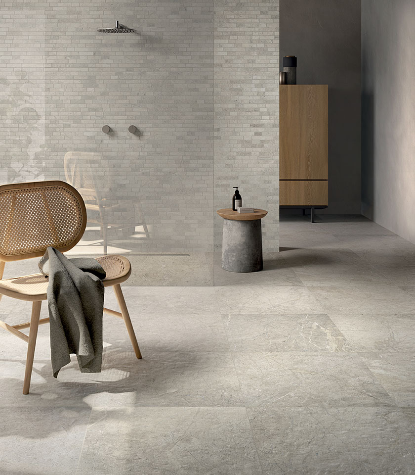 Minimal-Chic-Badezimmer mit hellem Boden in Steinoptik, strukturierter Wandverkleidung Ton in Ton, Walk-in-Dusche und reduzierten Holzmöbeln.