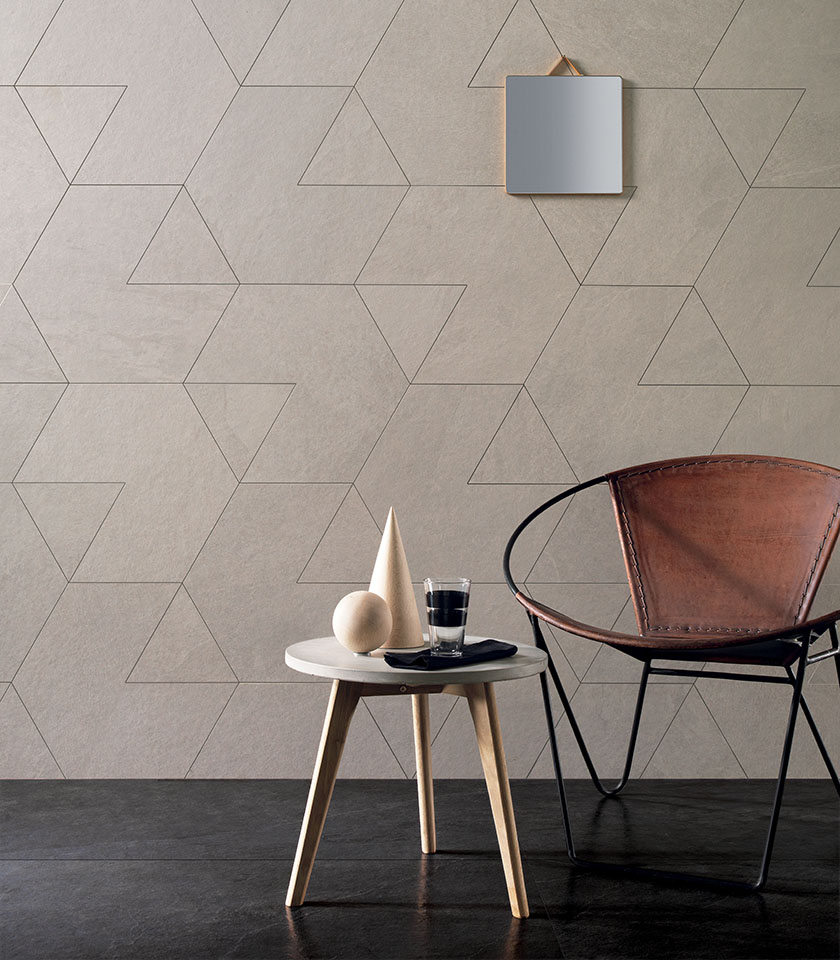 Wohnzimmer im Japandi-Stil mit geometrischer Wandverkleidung in Steinoptik, Ledersessel und minimalistischem Beistelltisch.